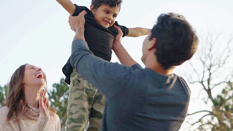 Family in the park, father holding up son.